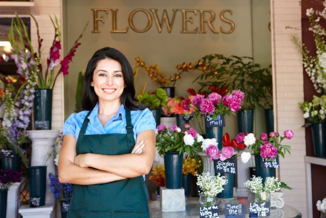 a woman standing in front of a flower shop.